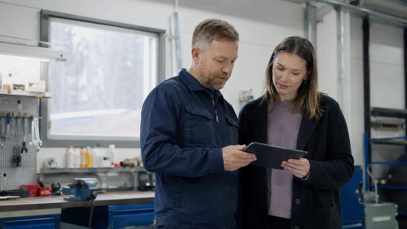 Yrittäjä ja taloushallinnon asiantuntija suunnittelevat tilitoimiston vaihtoa tabletilla yrityksen työtilassa