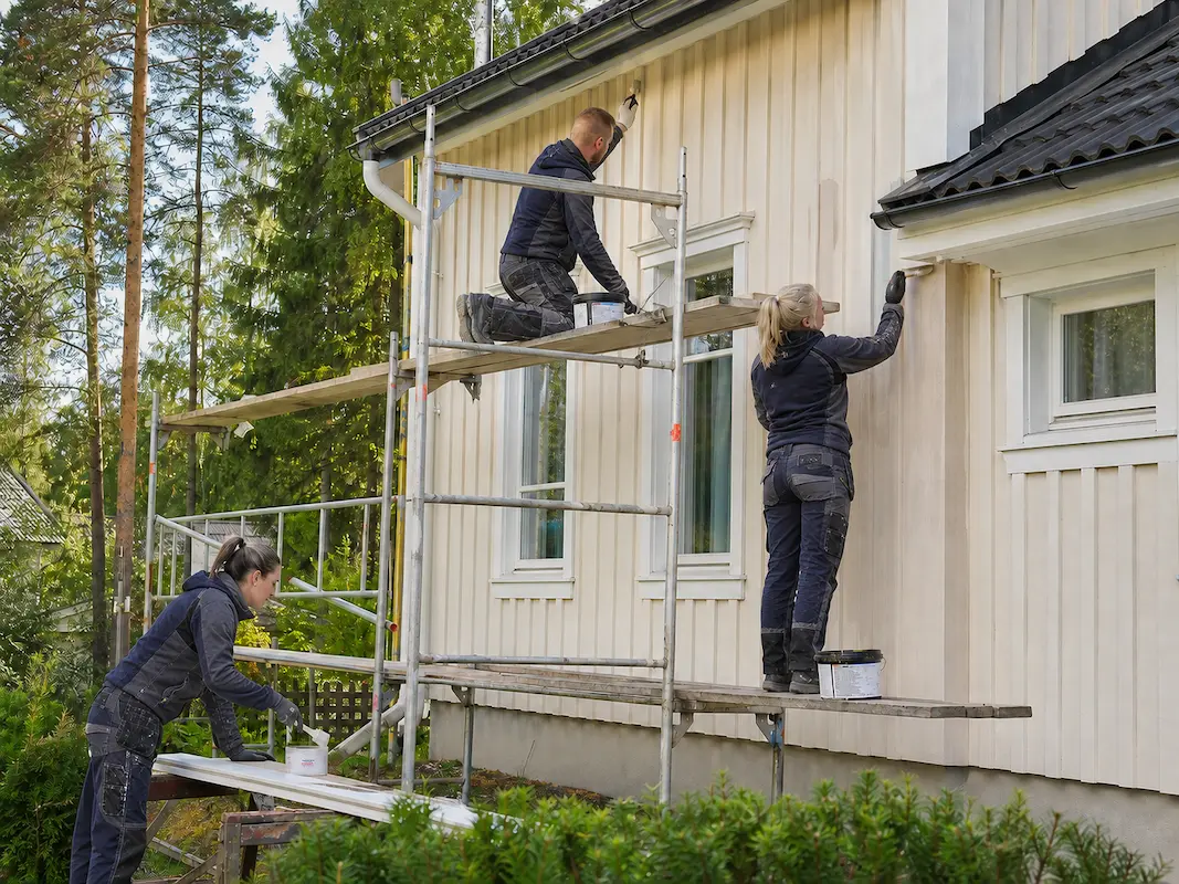 Maalausyrityksen työntekijät maalaavat omakotitaloa
